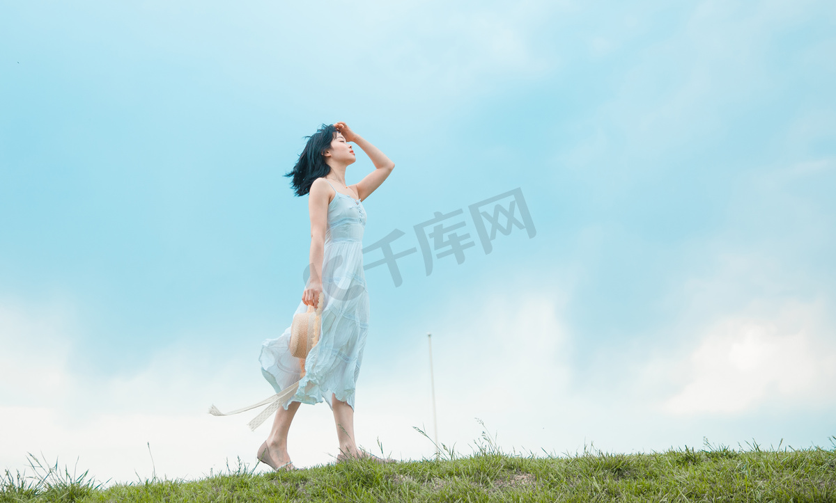 清新文艺白天穿着白裙子的美女户外草坪迎风走路摄影图配图图片
