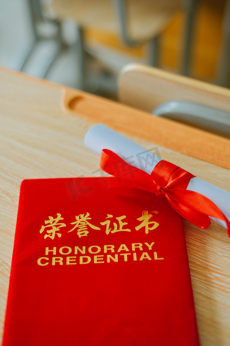 荣誉证书毕业季红色证书课桌上平放着摄影图配图图片