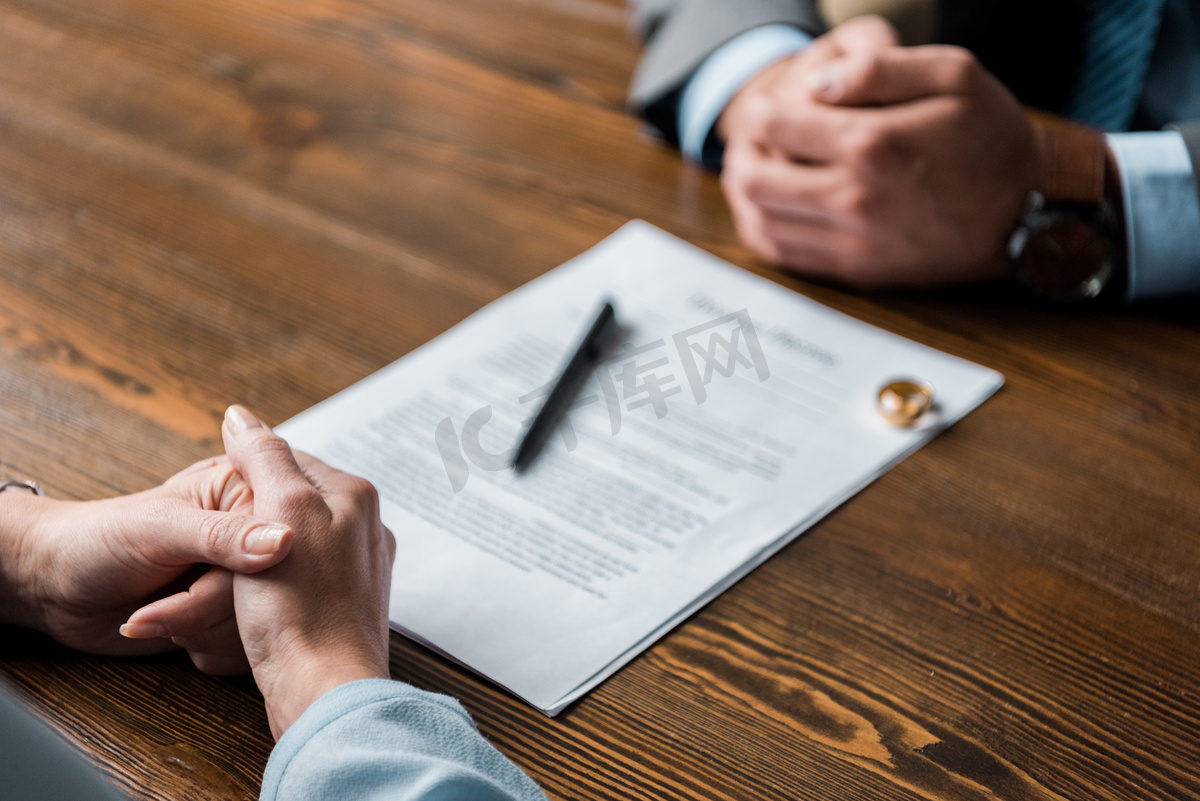 部分观点的律师和客户坐在桌子上与离婚令和结婚戒指 图片