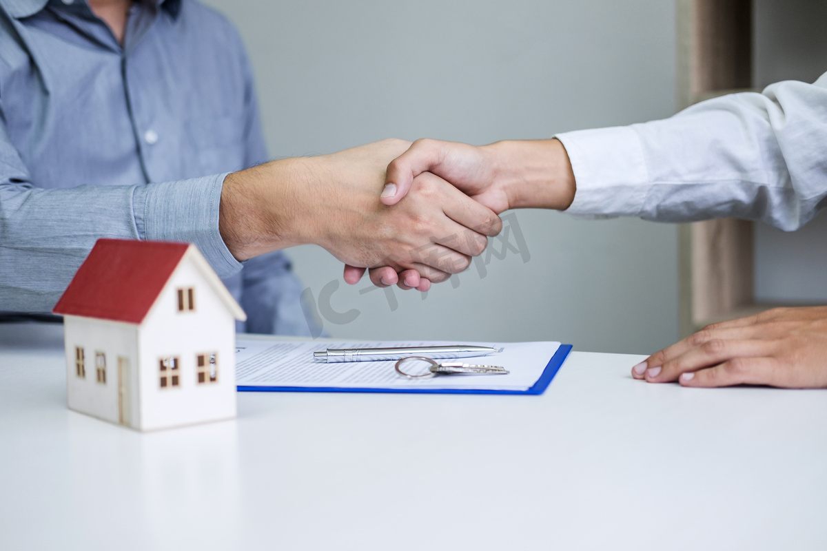 地产代理与客户在签订了房屋保险、投资贷款、握手及成功交易等协议后，携手庆祝合约的签订.图片