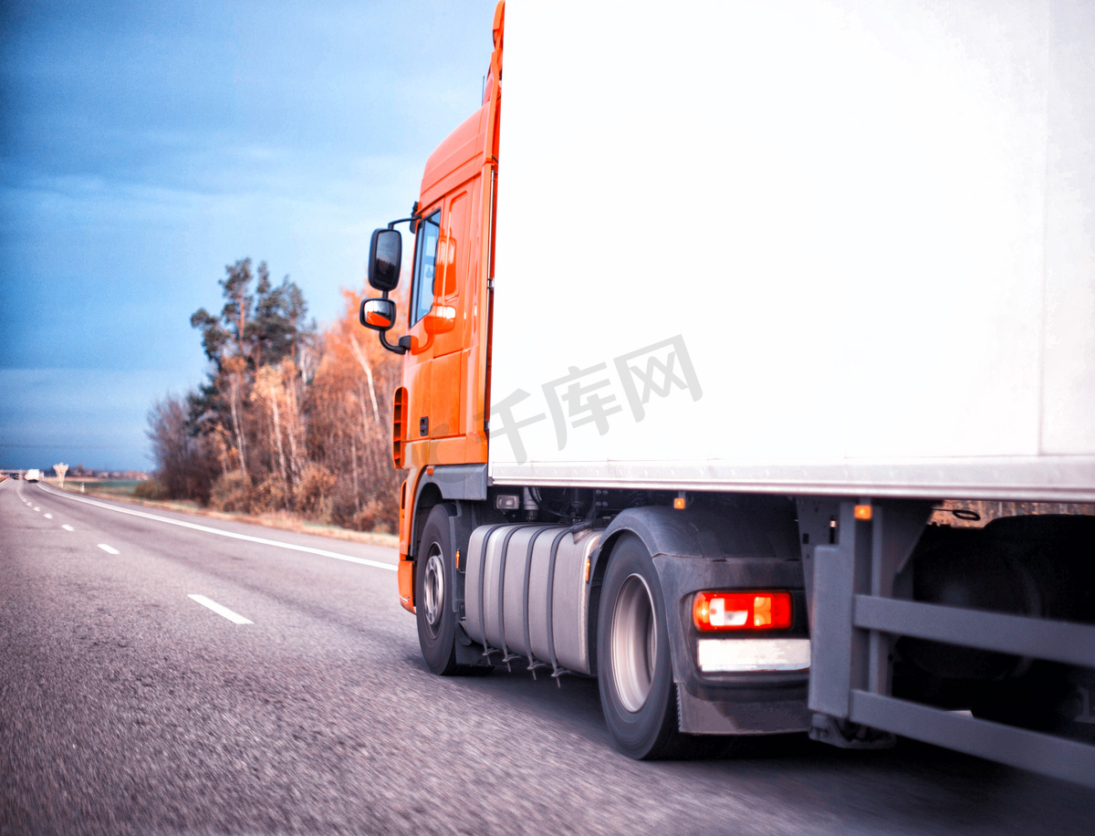 一辆橙色卡车正在高速公路上用冷藏拖车运送货物。货物运输中的物流和工业概念、司机代理、复制空间图片