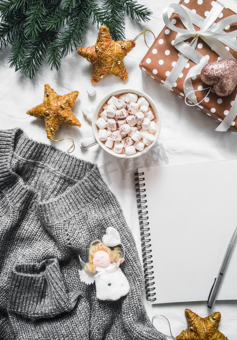 圣诞节规划背景-灰色舒适针织毛衣超大, 热巧克力, 圣诞礼物和装饰, 空白记事本上的光背景, 顶部视图。平躺图片