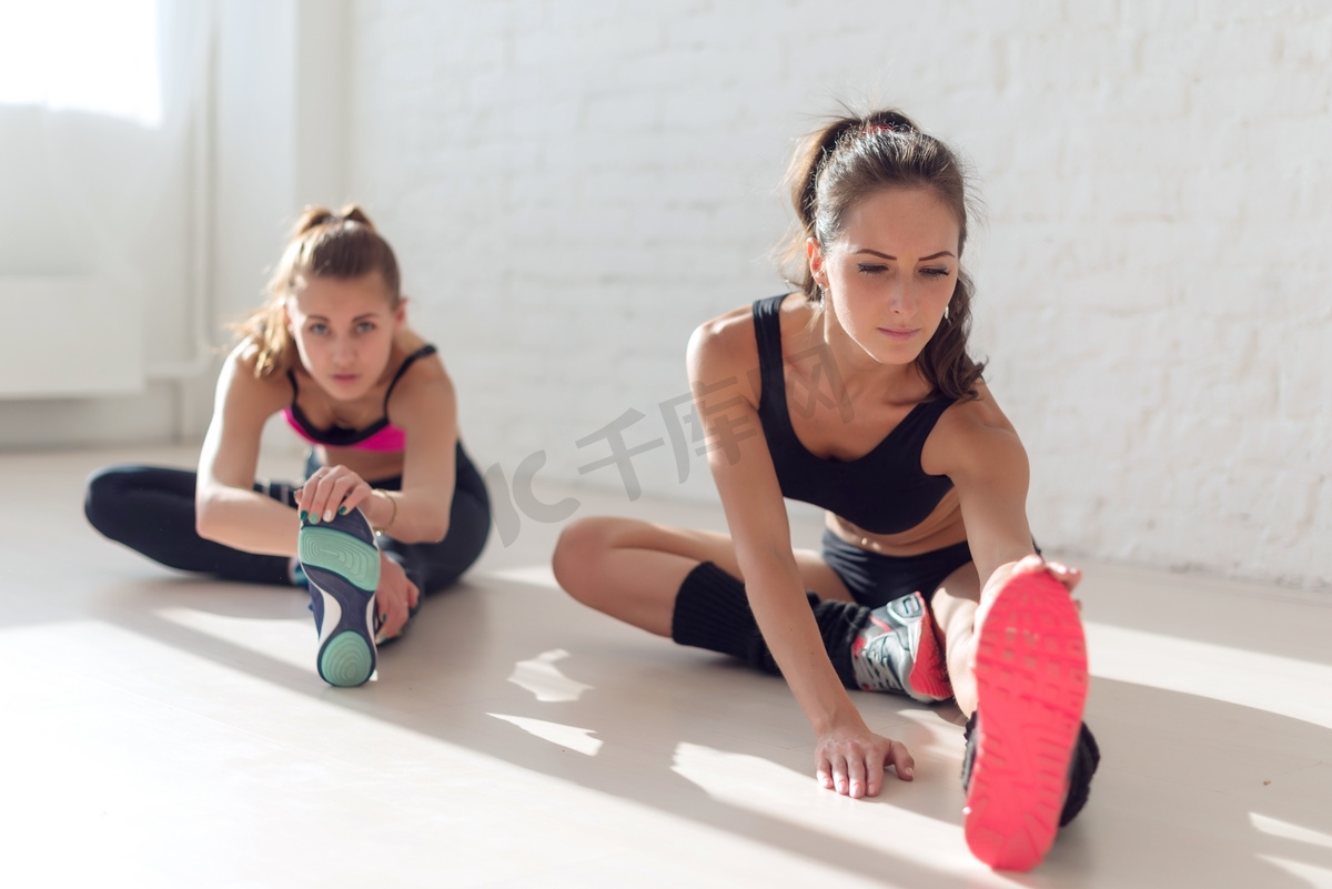 群适合妇女工作拉伸腿部肌肉回去热身在健身房健身、 运动、 训练和生活方式的概念.图片