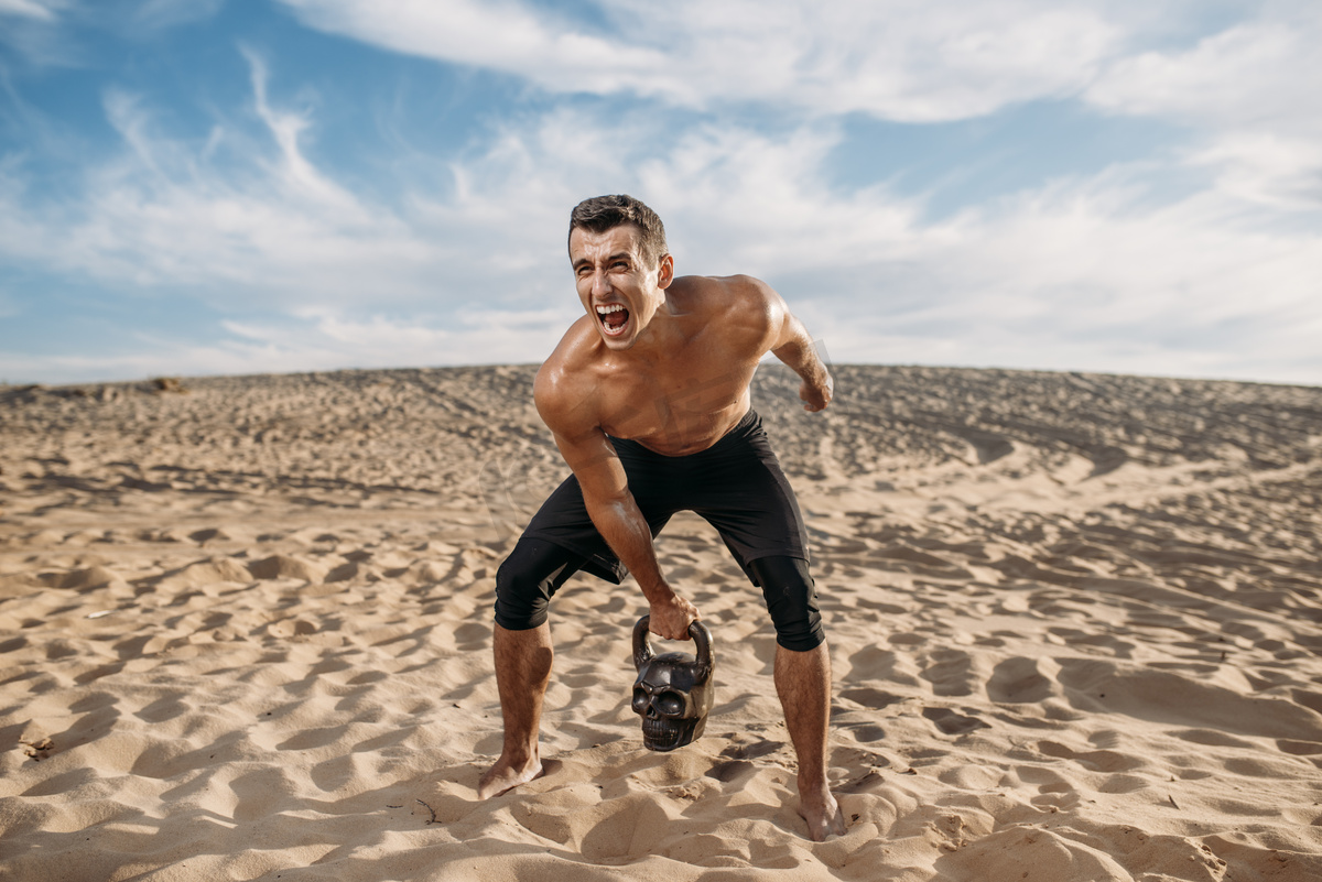 在阳光灿烂的日子里,男性运动员在沙漠中做举重运动. 运动的强烈动机，户外运动的力量图片