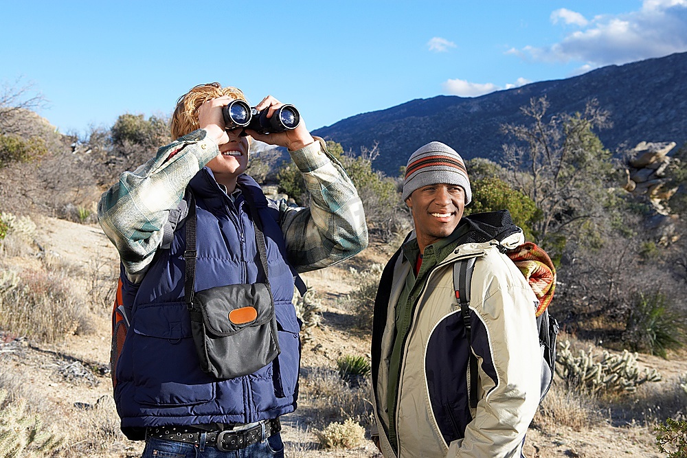 两名年轻人在山上徒步旅行时使用双筒望远镜图片