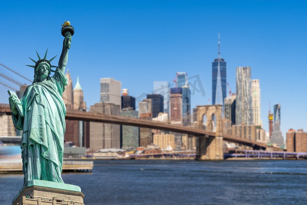 自由女神像与布鲁克林大桥和下部曼哈顿摩天大楼的背景为纽约市的建筑在纽约州NY，美国图片