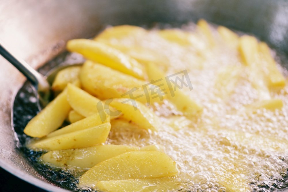 烹饪炸薯条或炸土豆在热油中的土豆角，关闭油炸土豆在平底锅上的油图片
