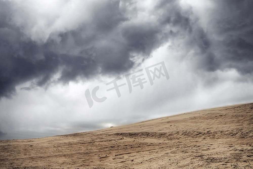 干燥沙漠中的沙尘暴在乌云密布的多云天空下图片