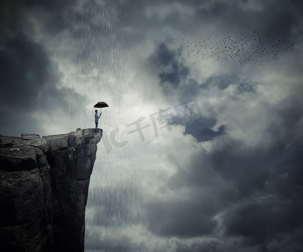 一个人拿着伞站在悬崖边，呼唤着下雨。云层之上的神秘地方。图片