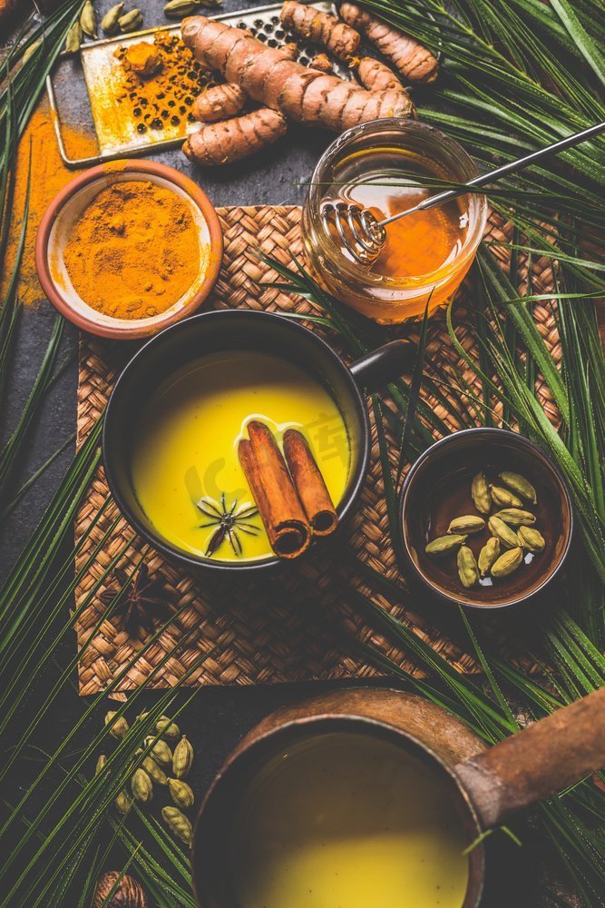 健康姜黄牛奶饮料由姜黄根，香料和蜂蜜制成。冬季热饮料。免疫增强补救，排毒和节食概念图片
