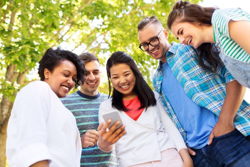 友谊，技术和国际概念—一群朋友与智能手机在夏季公园。快乐的朋友与智能手机在夏季公园图片