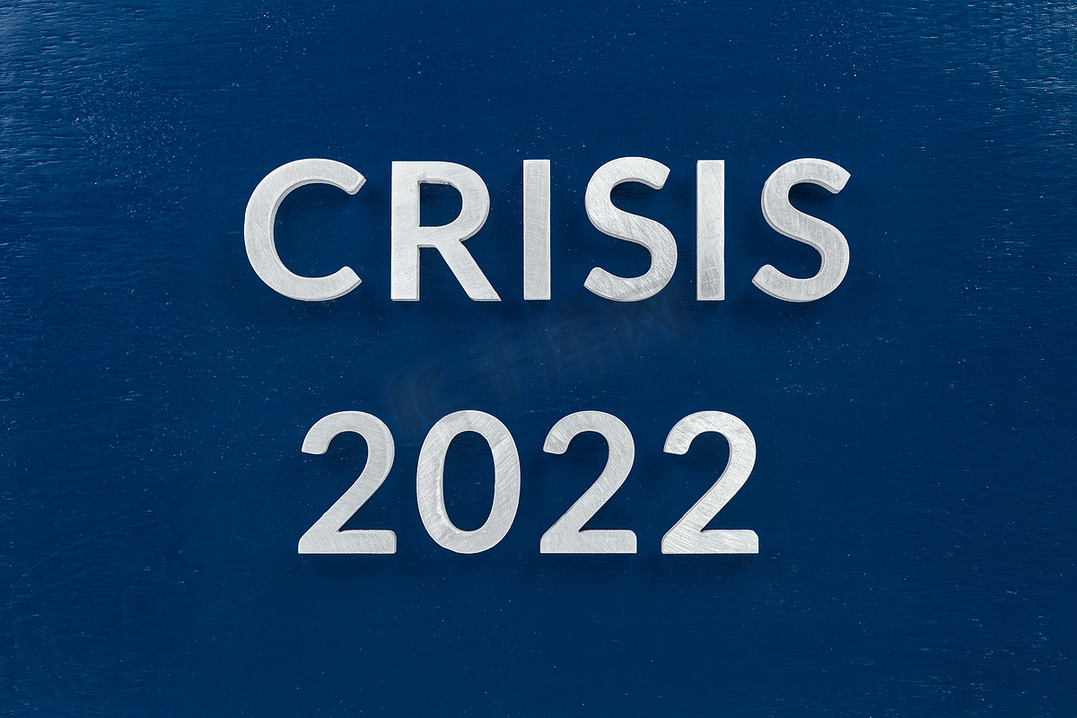 “2022 年危机”一词在蓝漆板上用发光字母铺设图片