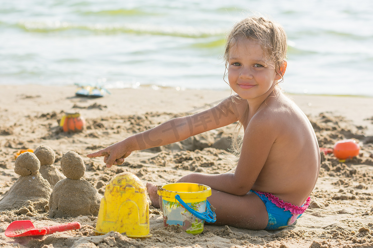 在沙子租用的蛋糕上，孩子在供水点的沙滩上感到高兴图片