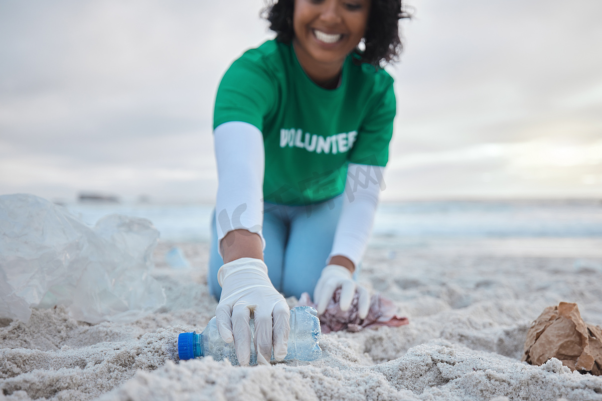 在清理过程中，手、瓶子和海滩上的一名志愿者妇女为社区、慈善或行动主义服务。图片