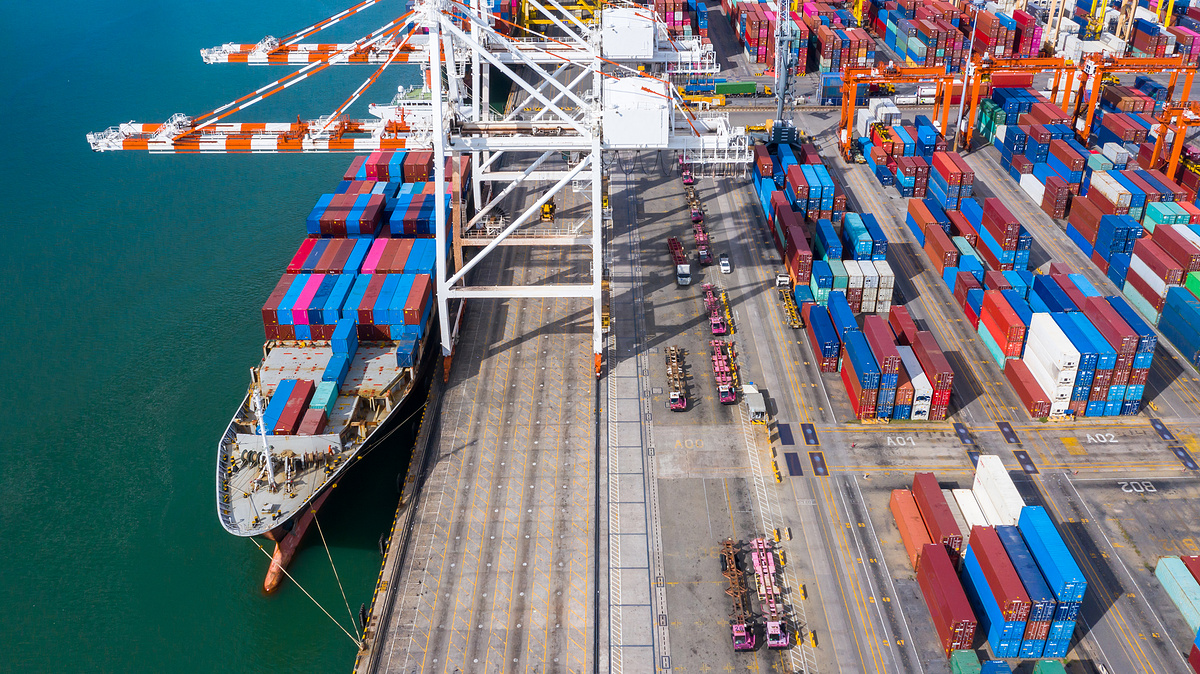 商业码头鸟瞰集装箱船，公司通过集装箱货船进口出口全球商业贸易物流和运输，货运海运港口码头。图片