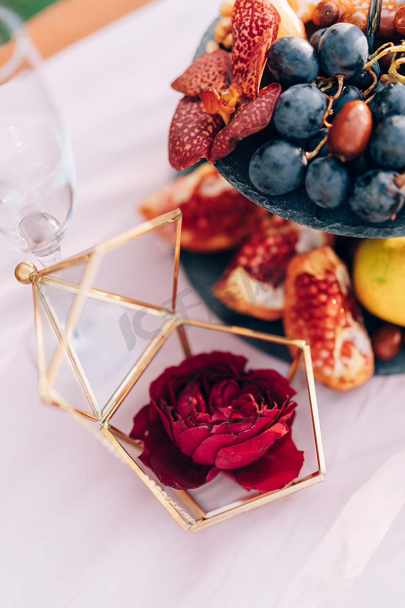 玫瑰在一个盒子里，一个盒子里装戒指，在婚礼上的桌子上放着葡萄和石榴。图片