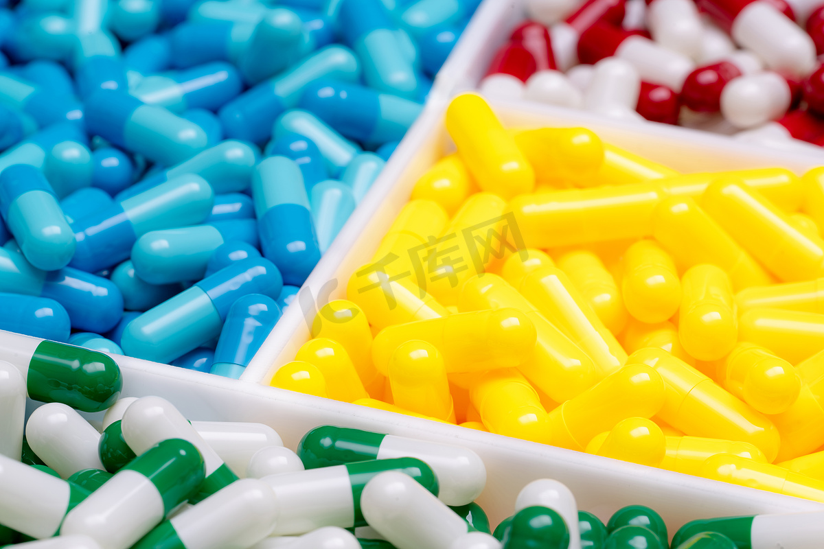 选择性地关注绿白胶囊丸在模糊的黄，蓝，红白胶囊丸。在医院合理使用的药物选择。制药工业。制药行业。药学图片