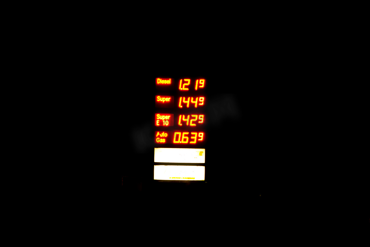 照明加油站标志与当前燃料价格在夜间被压缩图片