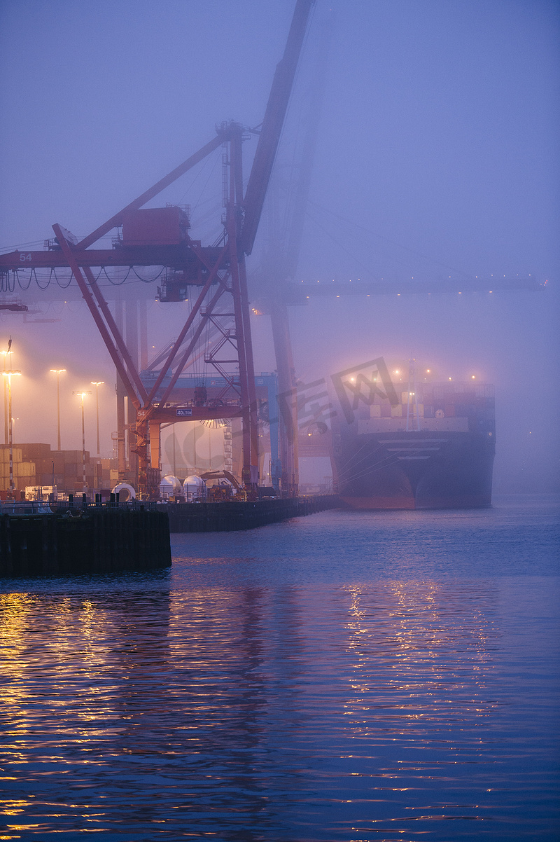 美国华盛顿州西雅图夜间海滨的货船和起重机雾蒙蒙的景象图片