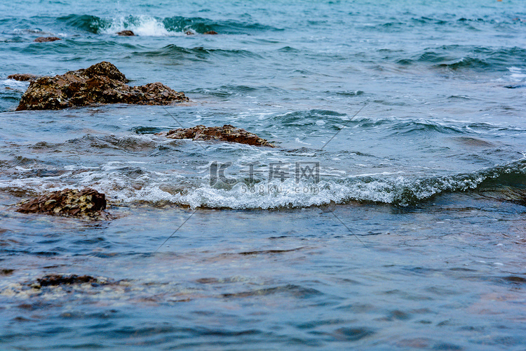 青岛傍晚大海礁石拍打摄影图配图