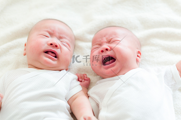 躺在床上正在啼哭的双胞胎婴儿  