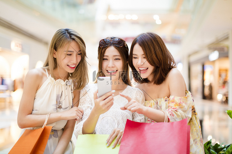 幸福的年轻女人看着智能手机在商