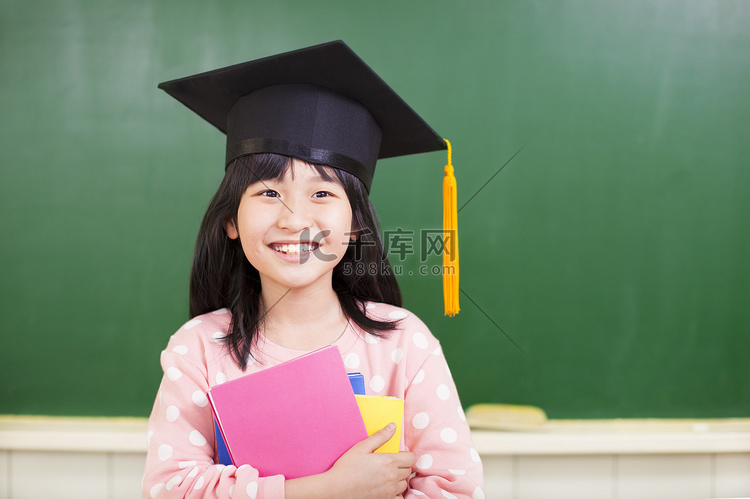 微笑女孩穿的毕业帽和拥有书籍