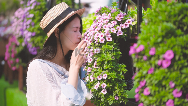 晴天花丛中的美丽姑娘在闻花香