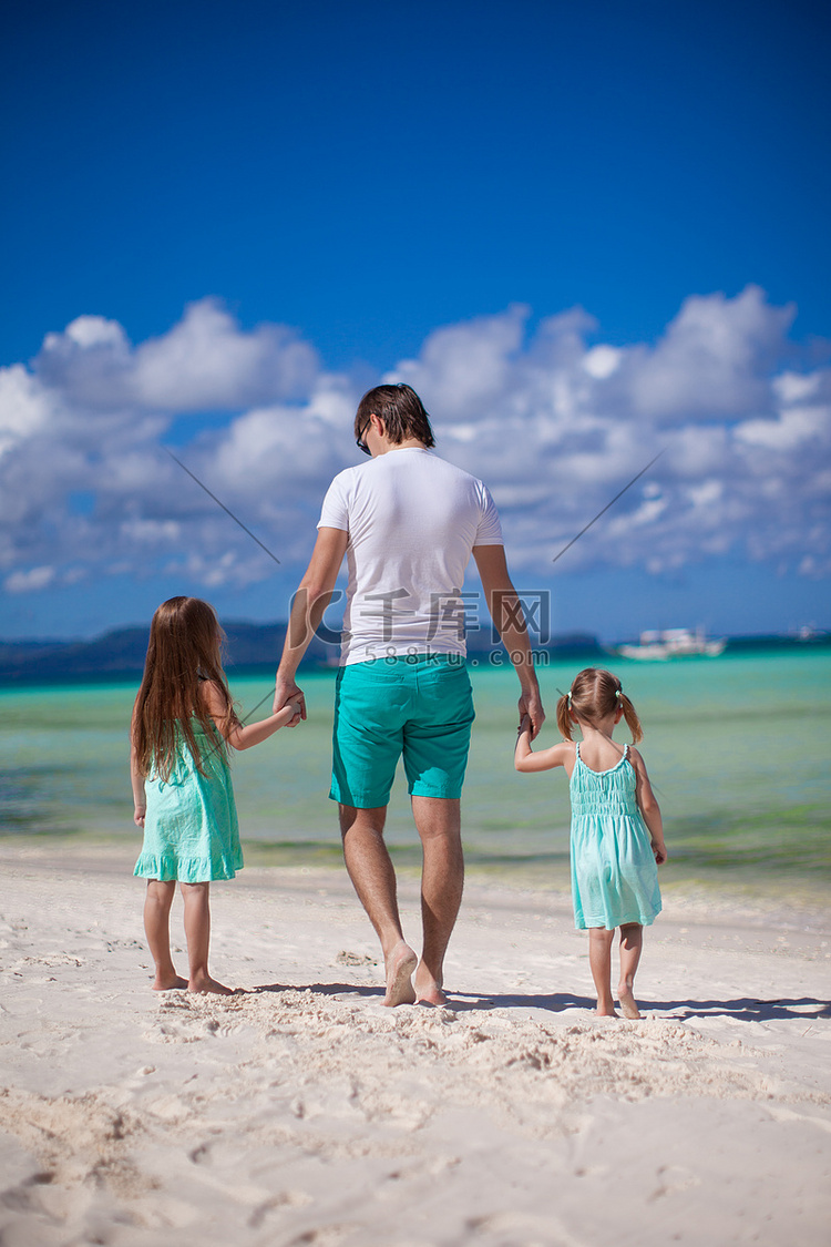后视图的父亲和两个小女儿在海边