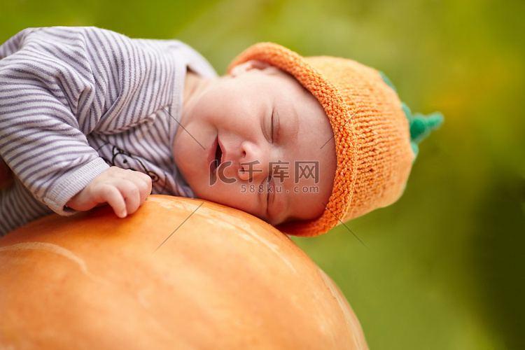 婴儿睡在橙色的大南瓜南瓜帽子