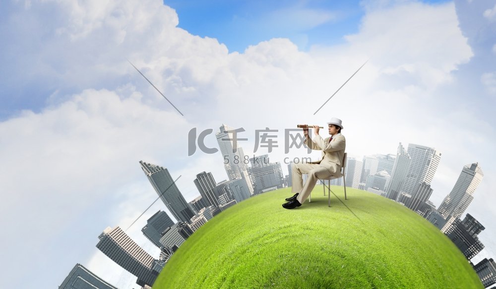 寻找未来的视角。一位穿着白色西装戴着帽子的商人坐在椅子上，看着望远镜