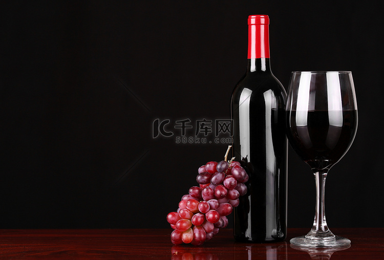 葡萄酒瓶和杯红酒配黑色的新鲜葡