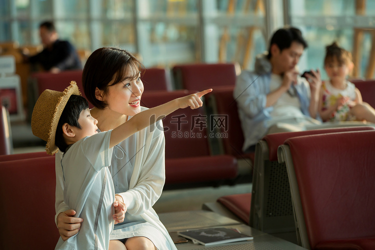 年轻妈妈和儿子坐在机场候机厅