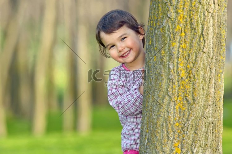 躲在森林里的一棵树后面的小女孩