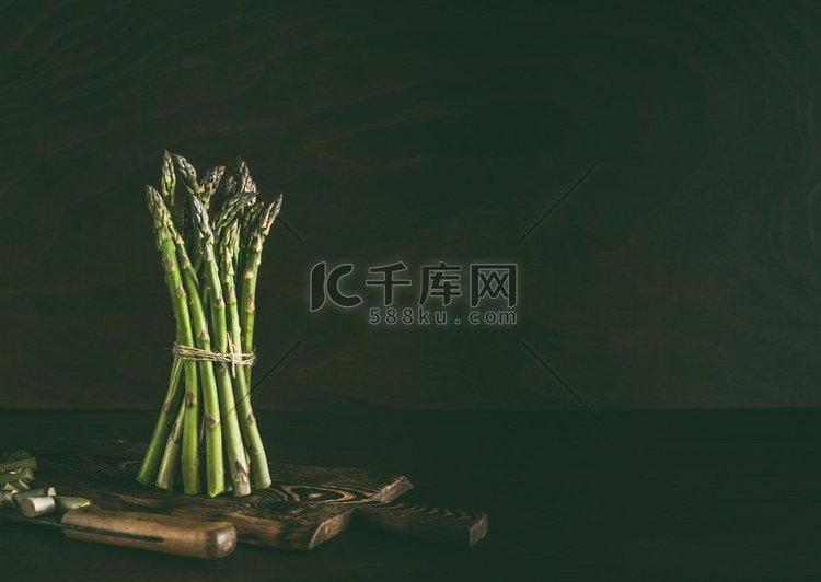 绿色芦笋束站在黑暗的乡村厨房桌