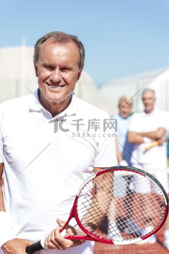 微笑的高级男子拿着网球拍的肖像