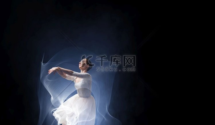 优雅的女舞蹈家在白色礼服反对黑