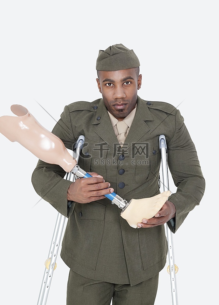 一名残疾军官手持假肢，拄着拐杖