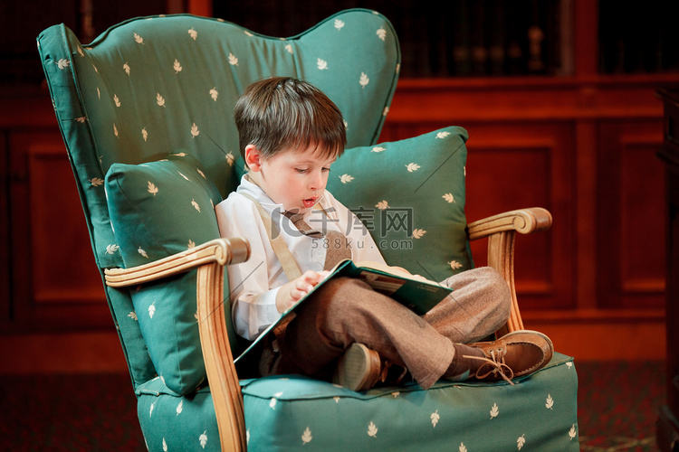 可爱的小男孩，读本书在扶手椅上