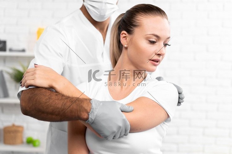 男性理疗师检查女性肩部