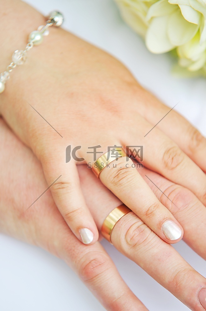 两只手戴着结婚戒指和鲜花