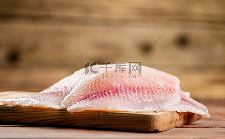 新鲜鱼片放在砧板上。在一个木制