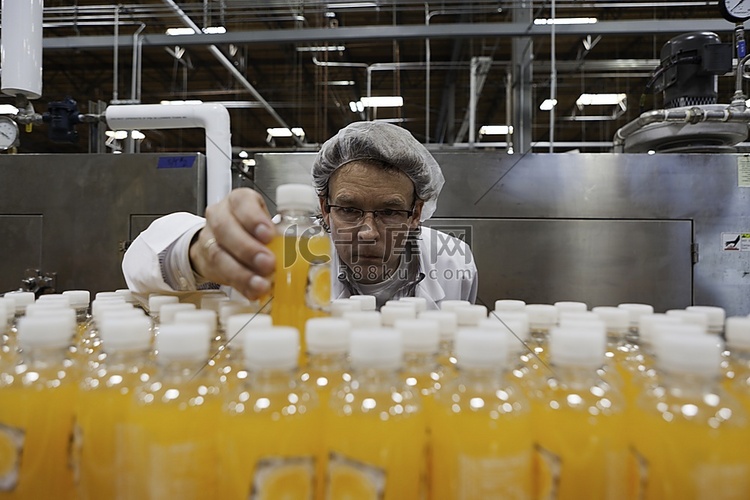 品管人员在生产线上检查果汁瓶