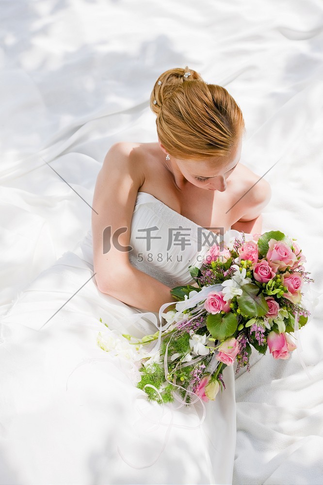 新娘坐在那里，手里拿着一束花