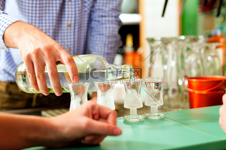 站在吧台上的酒保往玻璃杯里倒烈