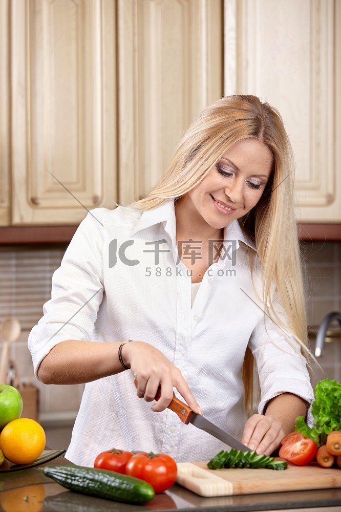漂亮女人在厨房切蔬菜