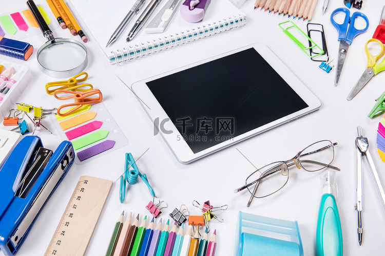 白色桌面上的学习用品和平板电脑