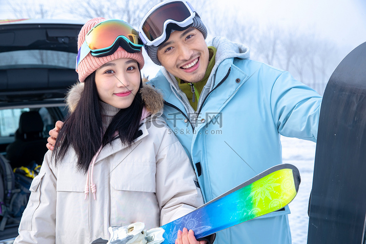 快乐的青年伴侣拿着滑雪板搂在一