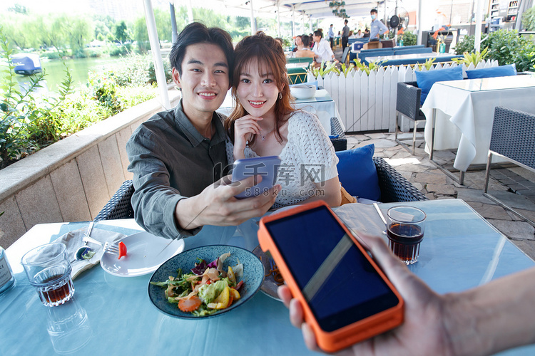 年轻情侣在餐厅用手机付款