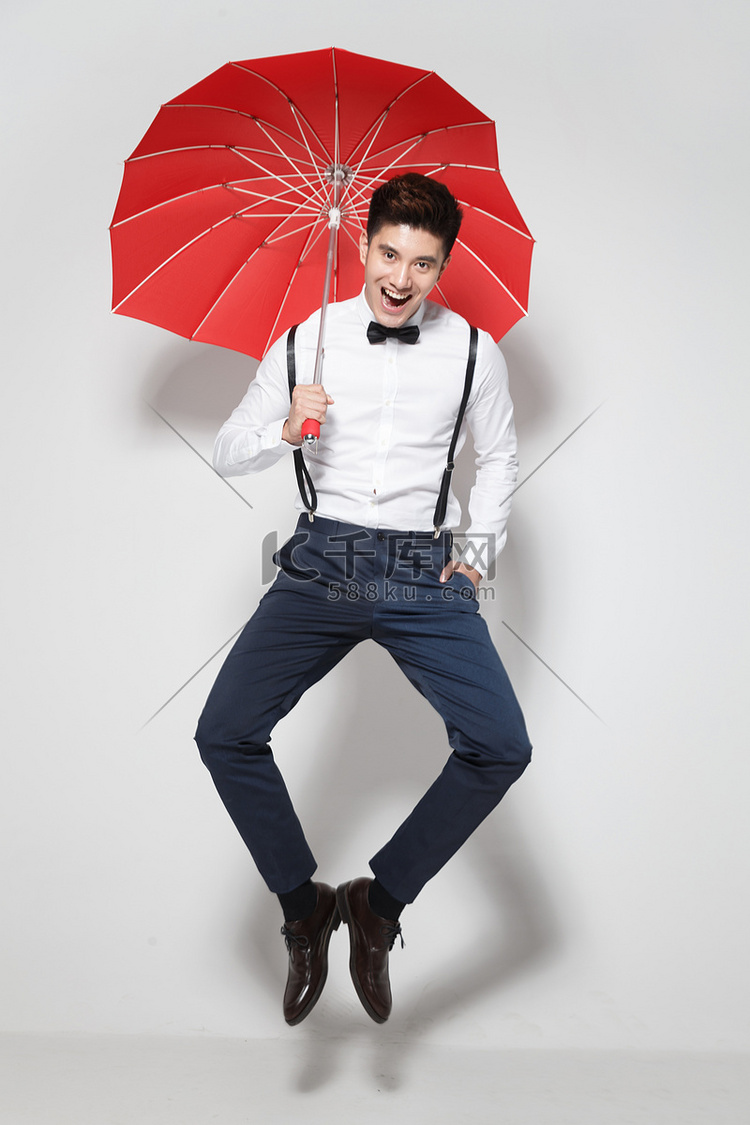 青年男人拿着红雨伞跳跃